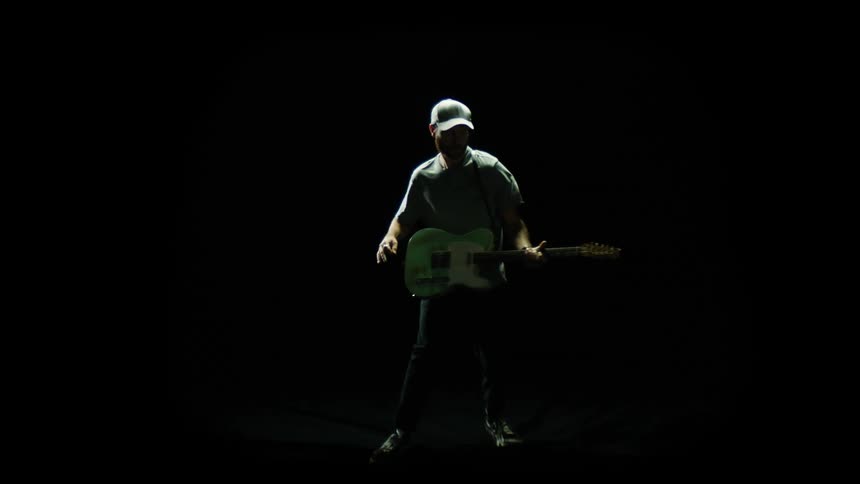 A man is playing the guitar in a dark room