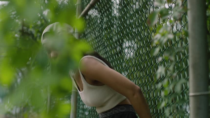 A woman is leaning against the fence