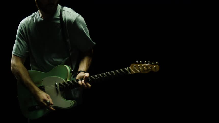 Man wearing a cap and a short sleeve shirt plays a guitar