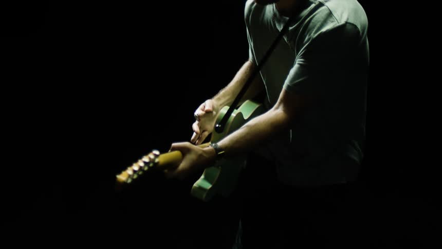 A man is playing the guitar in the dark