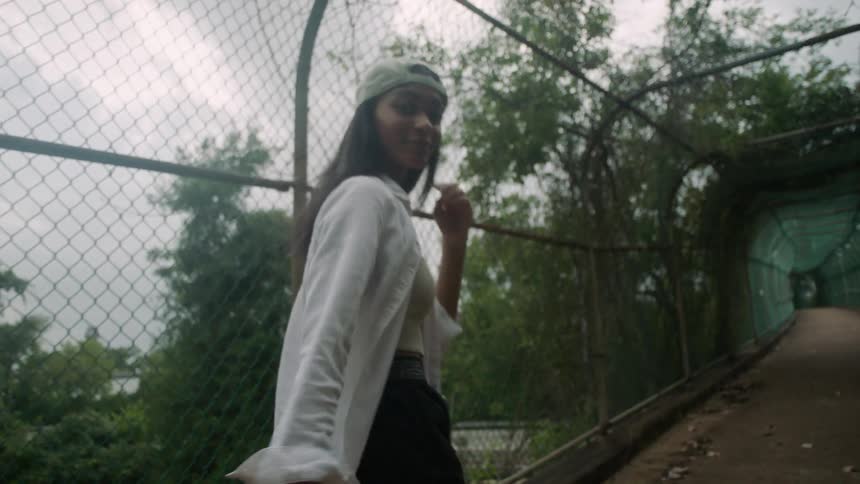 A teenage girl walking across a bridge turns around and walks backwards