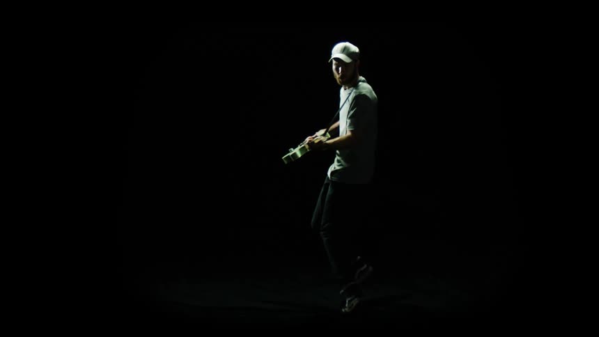 Man dancing around playing electric guitar in a dark room