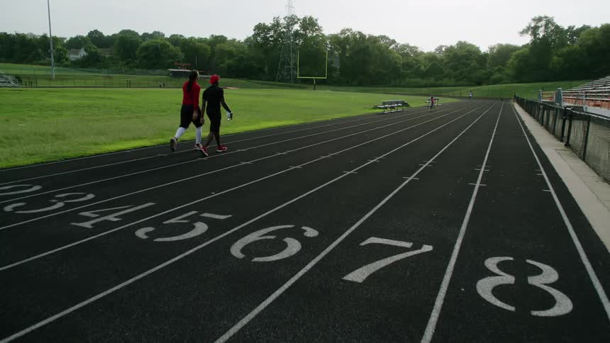 Two men walk on a track and field together