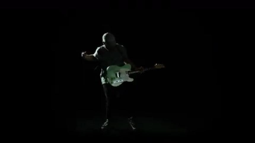 Man playing the guitar with flashing light in dark room