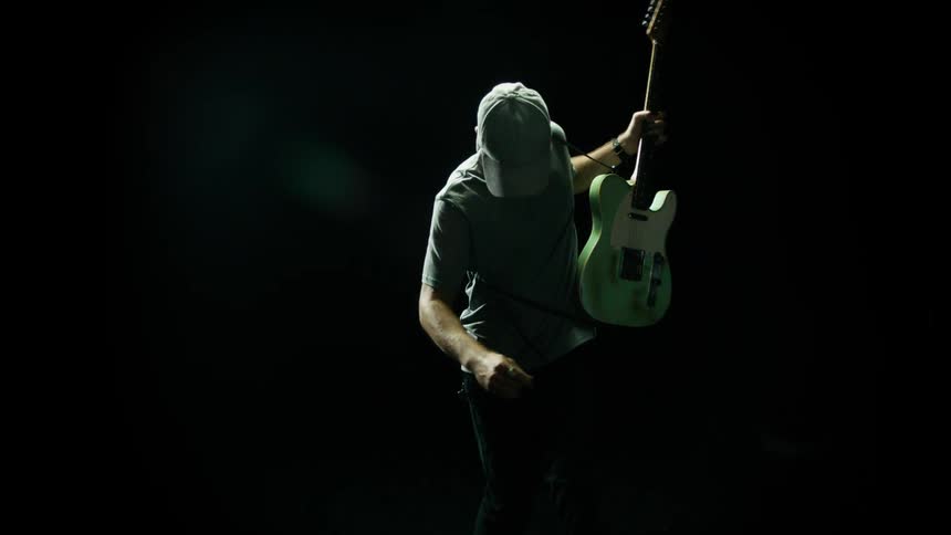 A man is playing guitar in the dark room