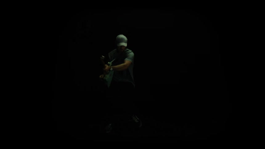 A guitarist makes exaggerated movements as he plays his guitar under flashing lights in a dark studio