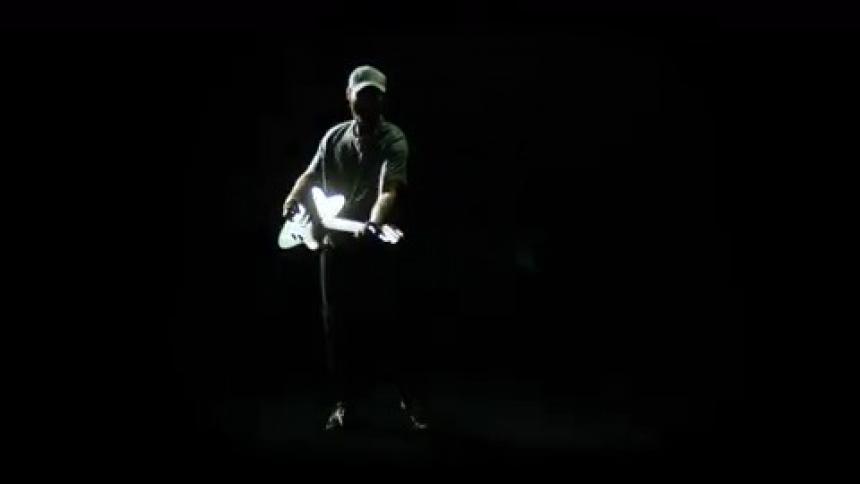 A man plays a guitar near a strobe light