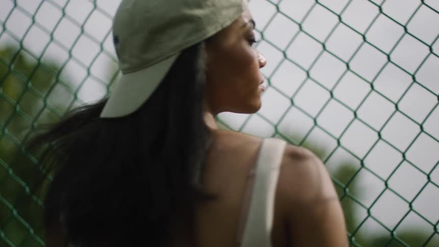 A woman is standing by a fence outdoors