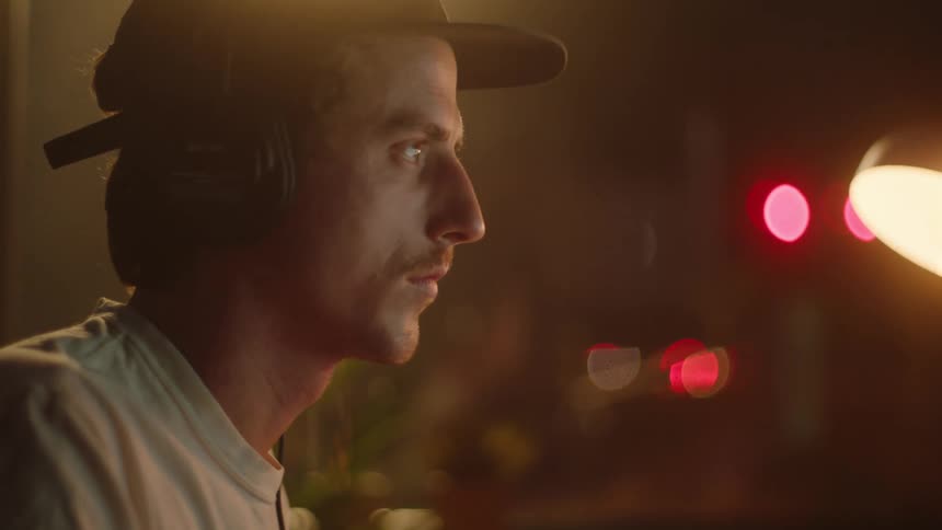 A man is wearing headphones in a room at night