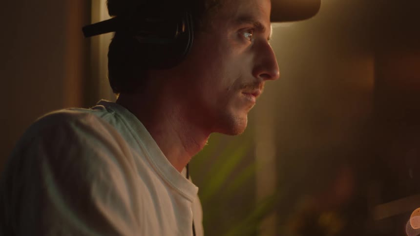Man wearing a brimmed hat and headphones rests his chin on his fist