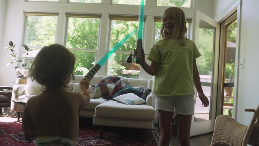 Two children playing around with toy light sabers having fun together