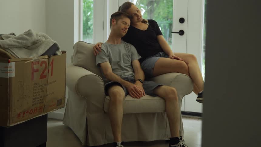 Two people sit on the chair together talking