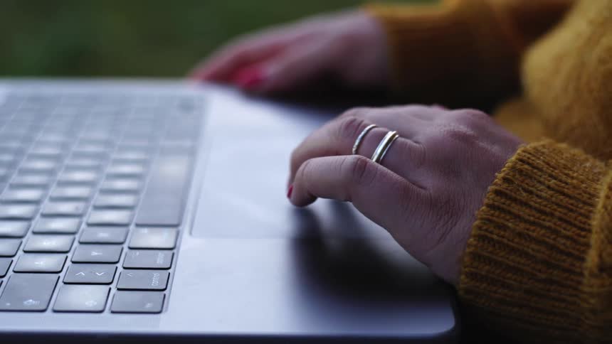 A person holding a laptop and using fingers on the touch pad
