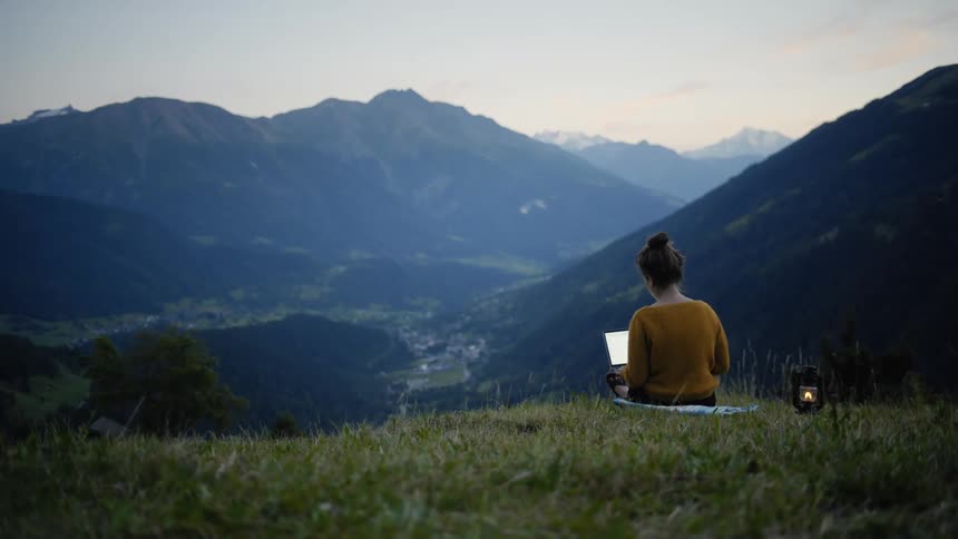 A woman is typing on a laptop outdoors in spring