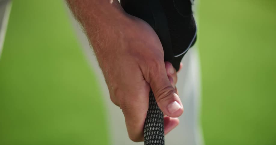 A golfer gripping a golf club while standing on a golf course