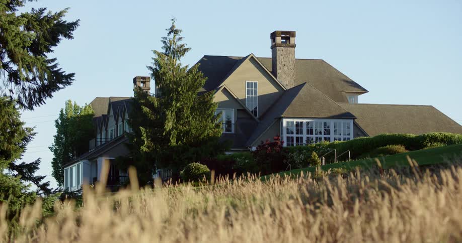 A nice house sits on land with trees and a blue clear sky