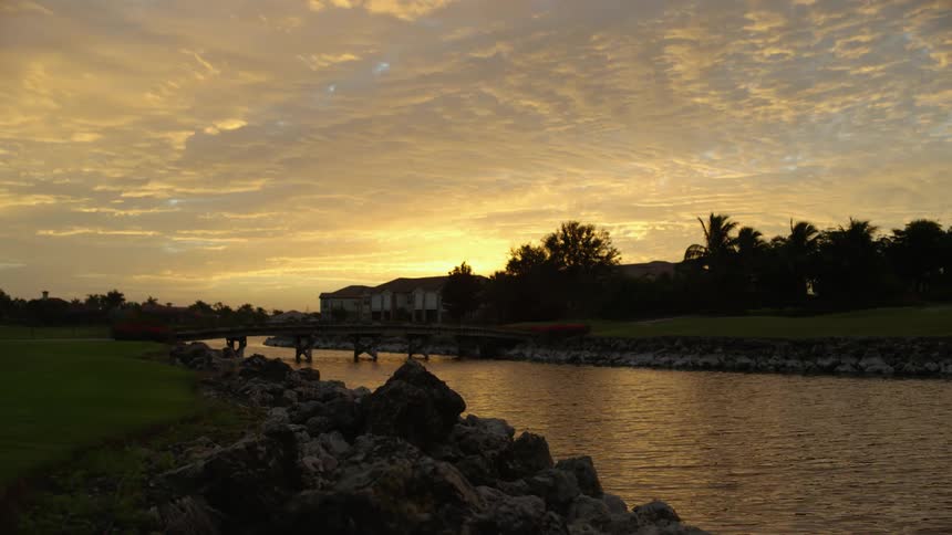 A bridge over a river with houses trees the sky and clouds in the background