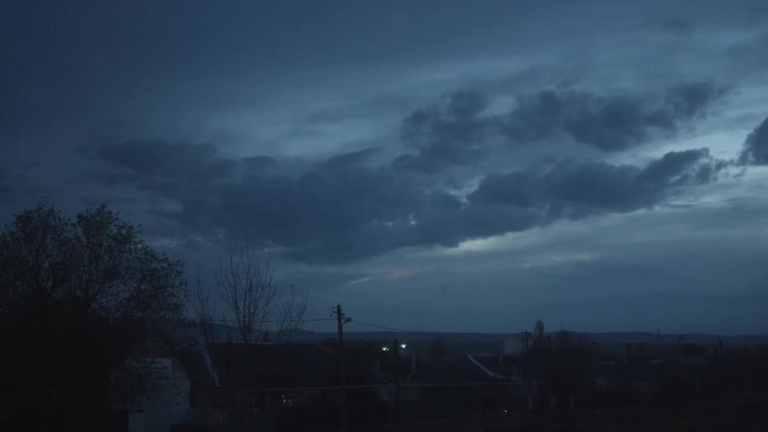 Thunder flashes in the storm clouds over a city neighborhood in the evening