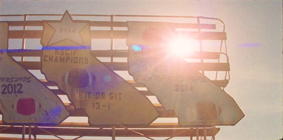 Sun shines through railing on seating holding line of plaques for sports victories plaques showing