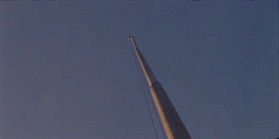 A tall flag pole displayed with a line swaying in the breeze