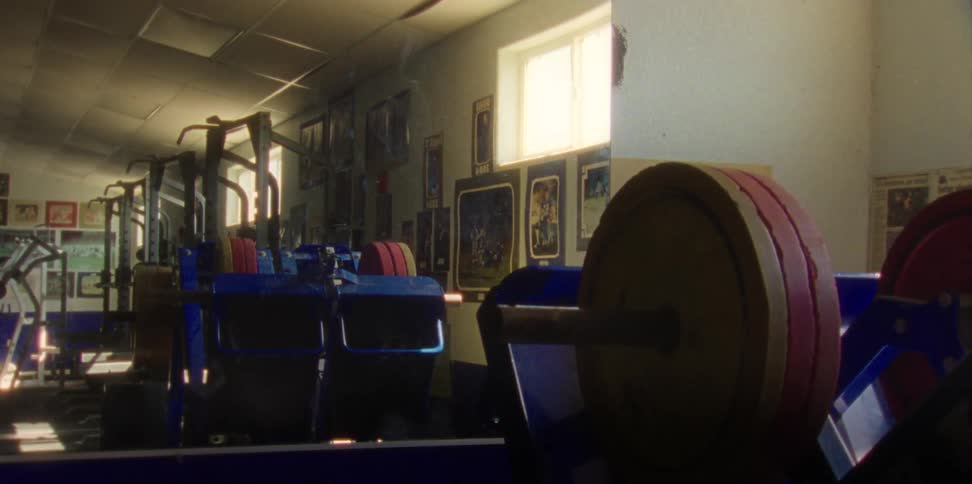 A weight room with a mirror on one wall and framed posters on other walls