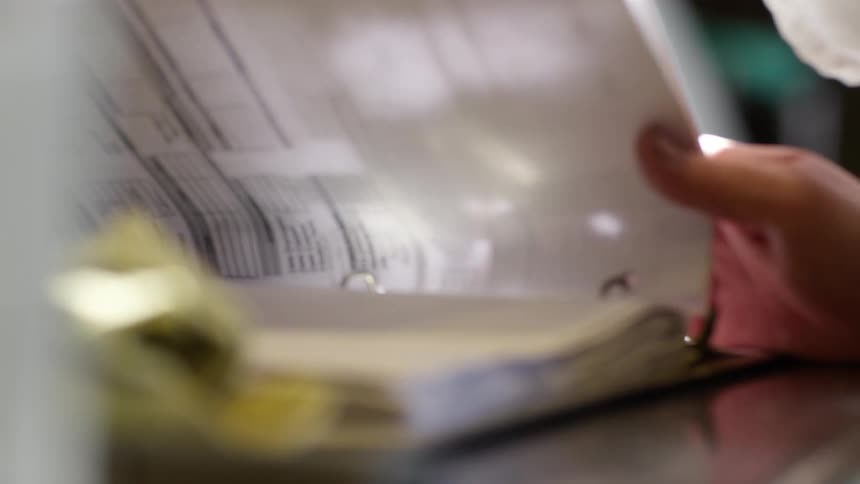 A man in an office writes in a book
