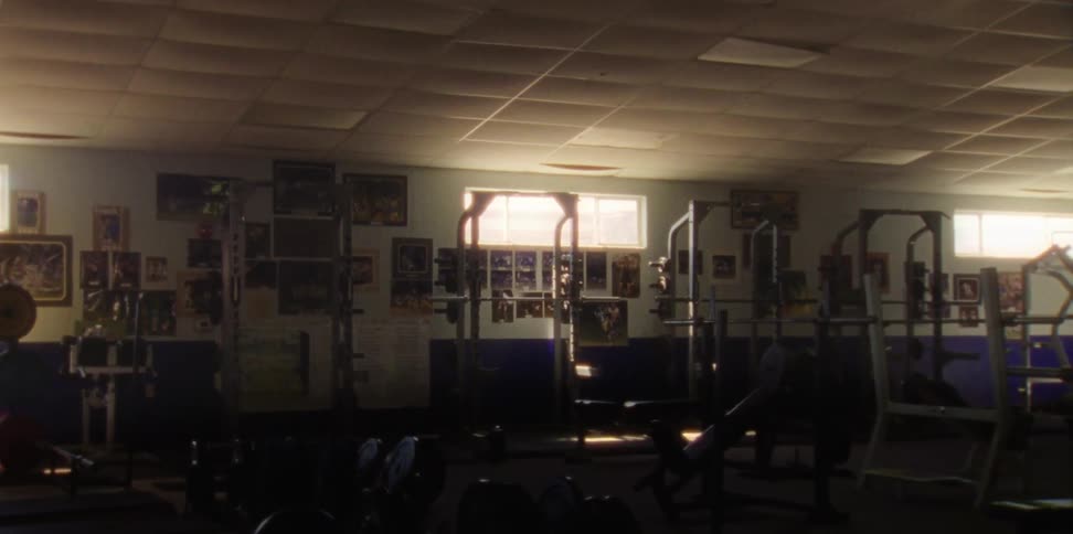 Framed pictures line wall under windows of exercise equipment filled gym