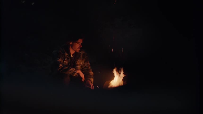 A man sits in front of a fire