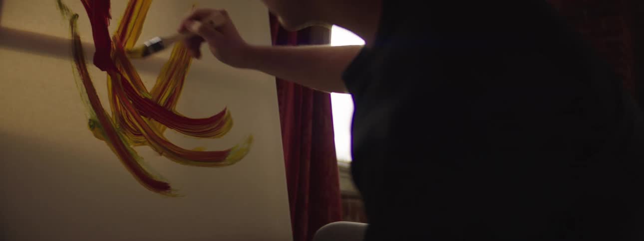A man is painting on a canvas indoors
