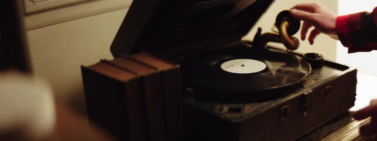 A person removes a record from a record player