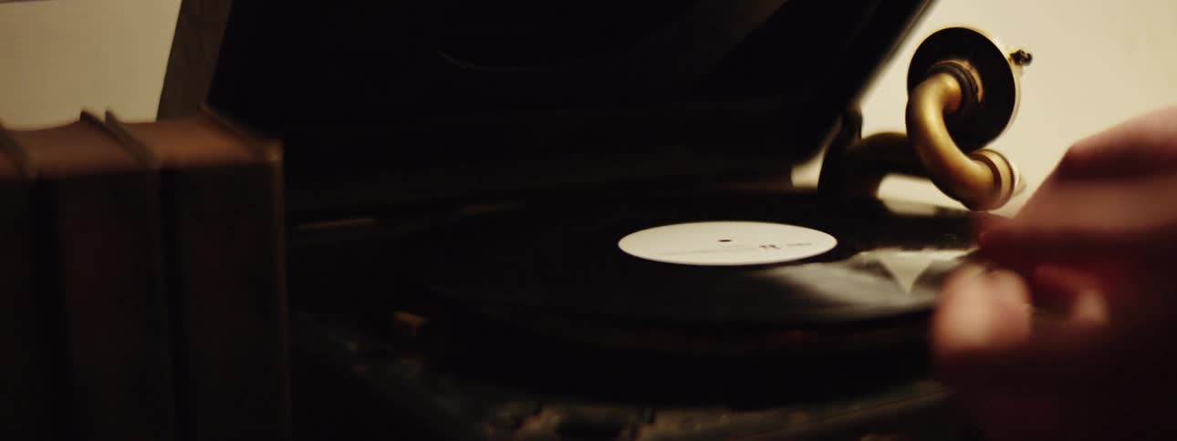 A person puts a record onto a dusty record player