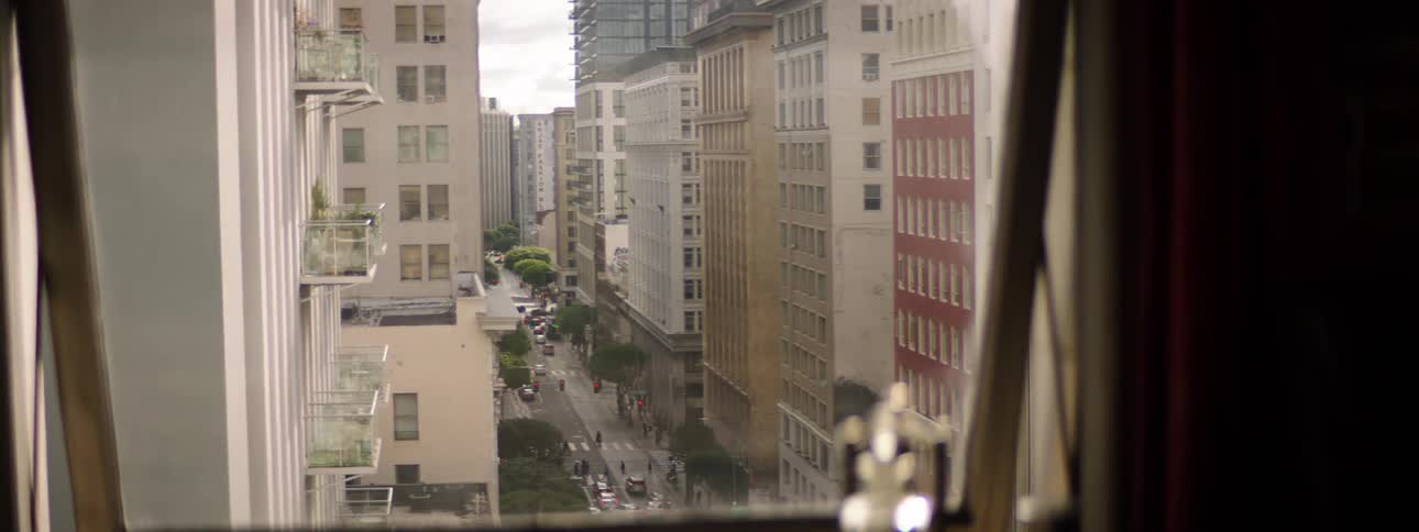 A view of a city street with cars people and apartment buildings