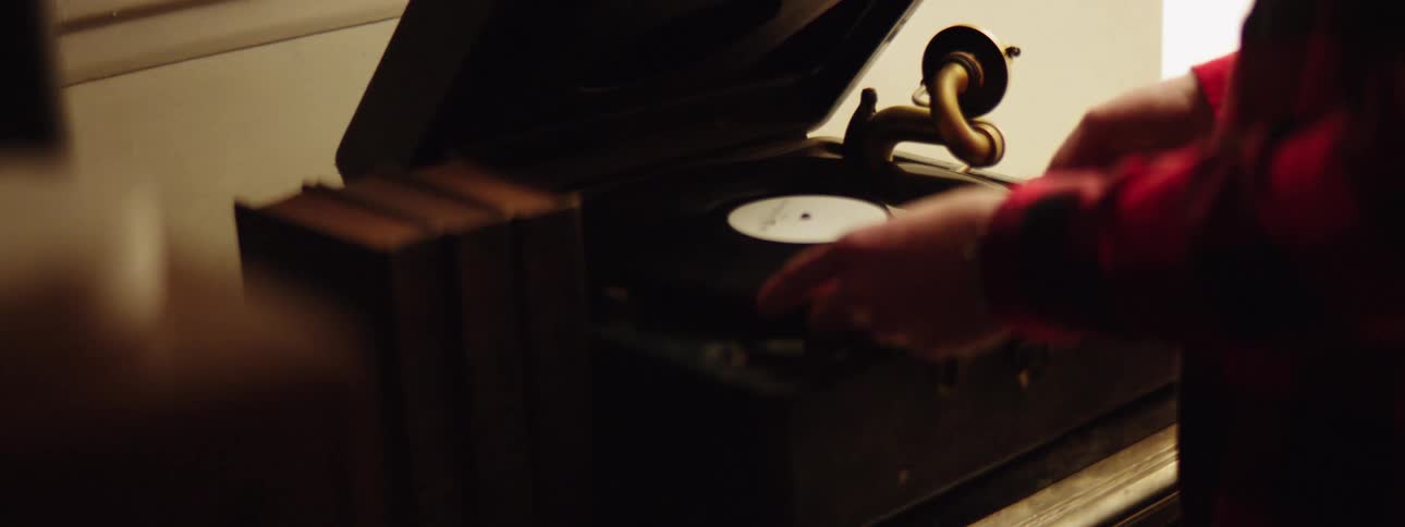 A woman at home puts a record on a vintage record player