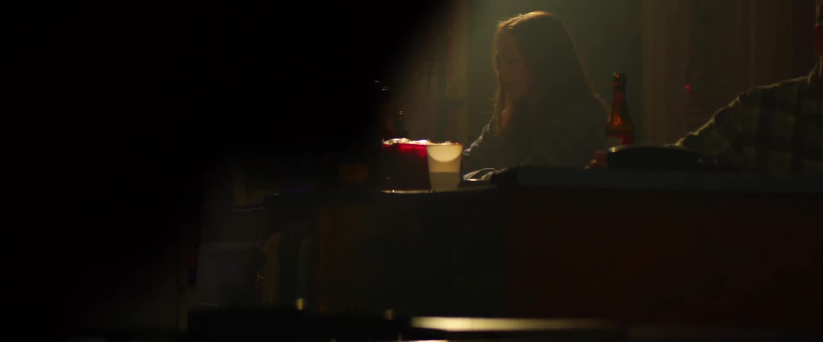 Caucasian woman sitting in a bar drinking an alcoholic beverage in a bottle