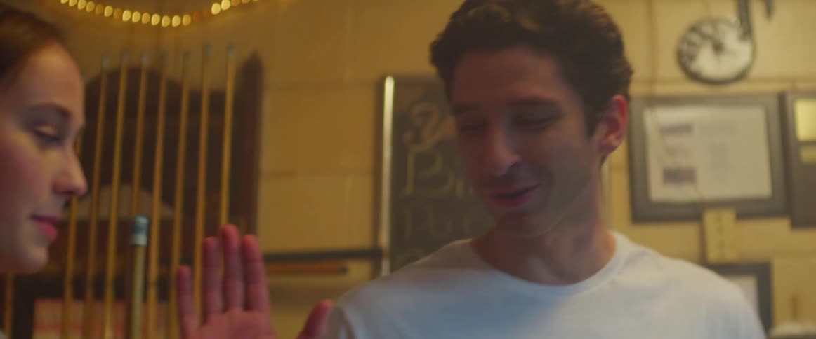 A man high fives a woman while she is holding a pool stick