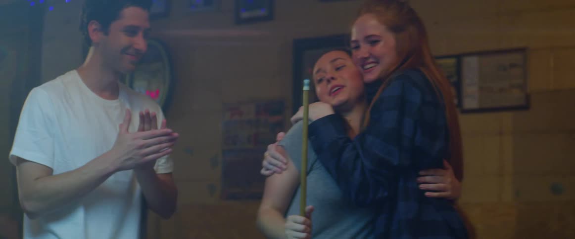 A group of friends celebrating and hugging while plaing pool in a bar
