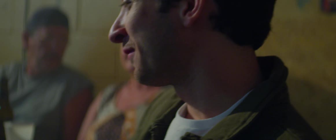 A smiling man talks with the other patrons while drinking in a bar