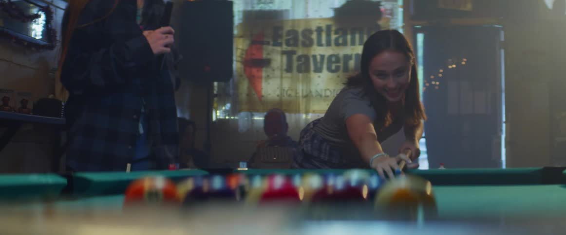 Two women and a man playing pool on a pool table
