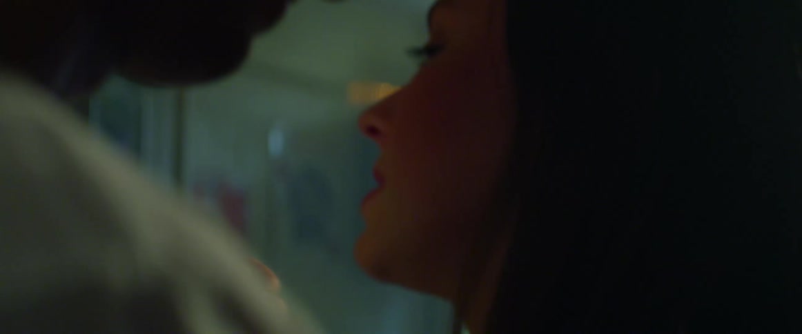 A man and woman dance and talk with one another in a dimly lit room