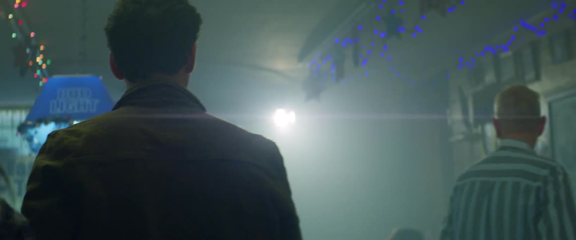 A man in a bar smiling and talking to a woman then walking with her