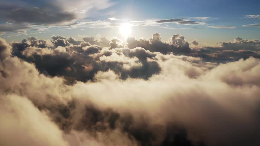 The sun is setting in the horizon above the clouds