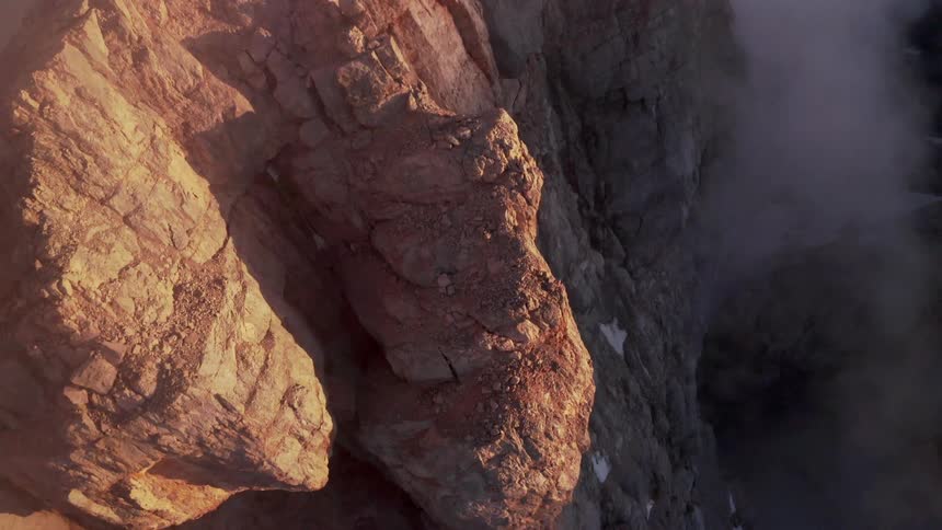 An aerial view of a rocky cliff with snow on a winter day