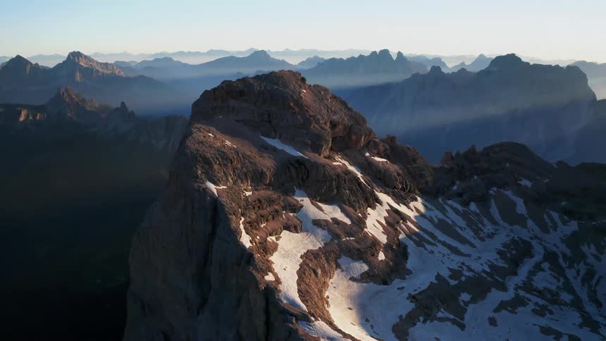 An aerial view of a snowy mountain range in nature on a cold winter day