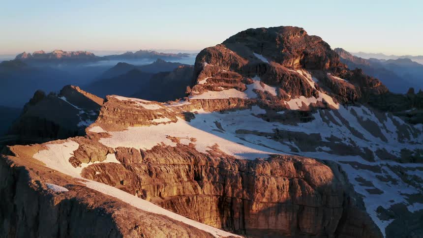 A mountain range with snow and ice with the sky and clouds in the background