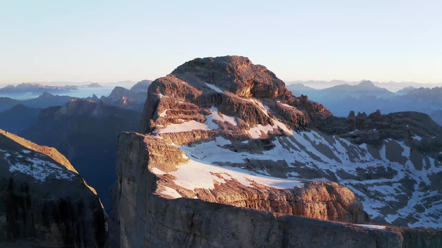 A mountain range with snow and ice with the sky and clouds in the background