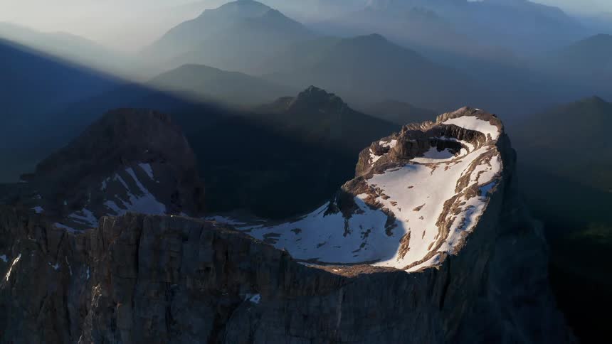 Snowcovered caldera with a high ridge around set in a misty mountain range with sunlight