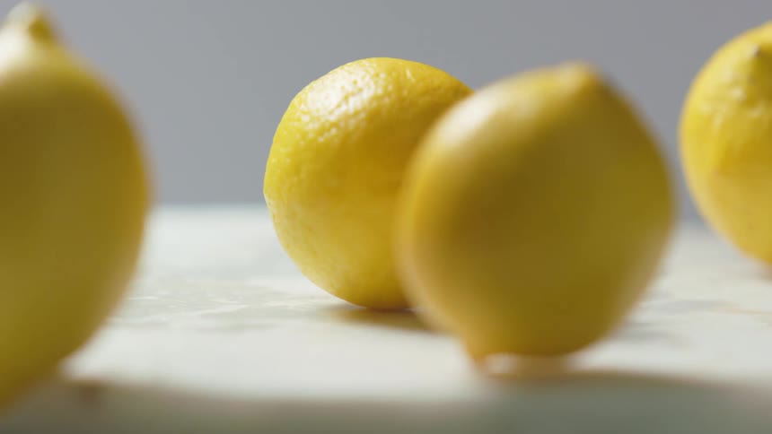 Lemons falling and rolling off a white surface with a gray background