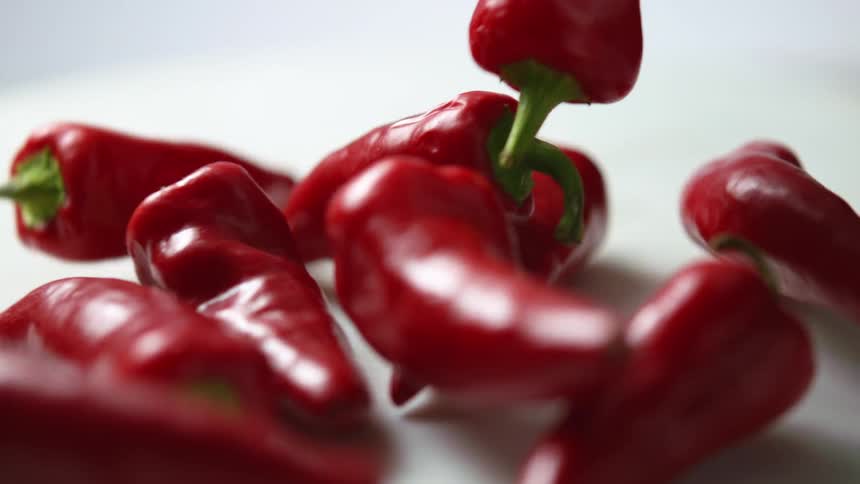 Chili peppers falling on a white surface