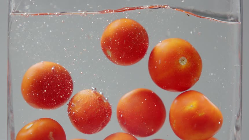 Several tomatoes are submerged into a vat of water and left there by an unknown source