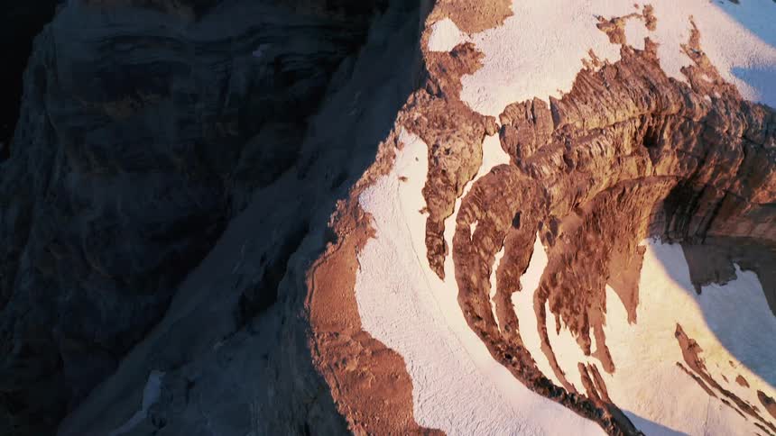 An aerial view of snow covered mountains in the wilderness at sunrise